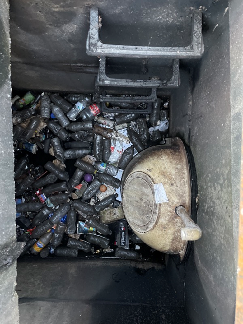 A storm sewer filled with discarded bottles and cans.